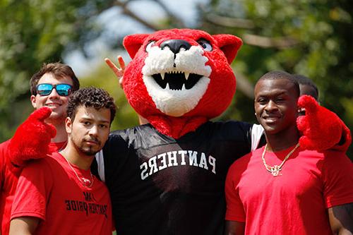 Pouncer stands with three young men dressed in red